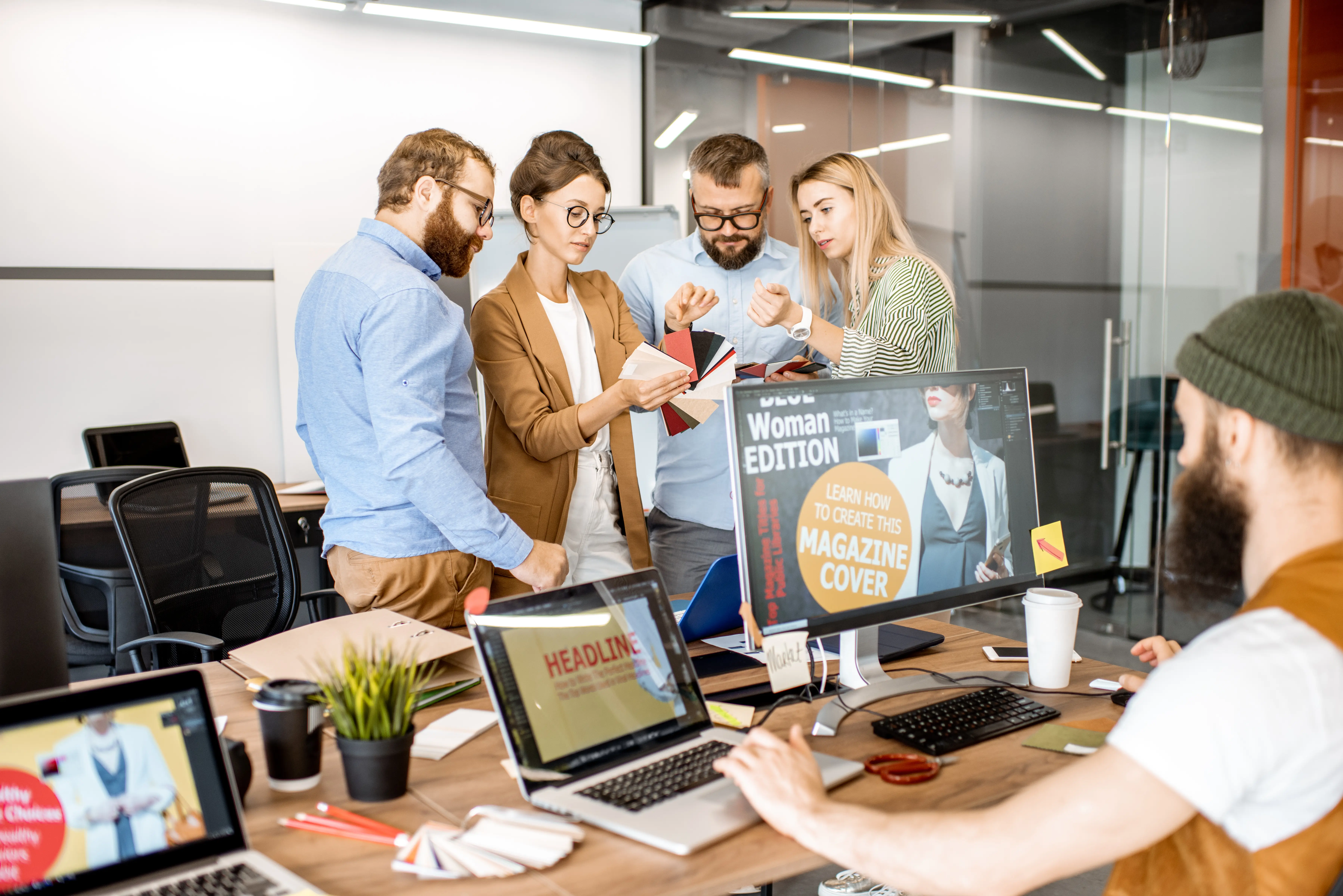 A creative team collaborating in a modern office, reviewing design materials, branding concepts, and visual assets while discussing project strategy and creative direction.