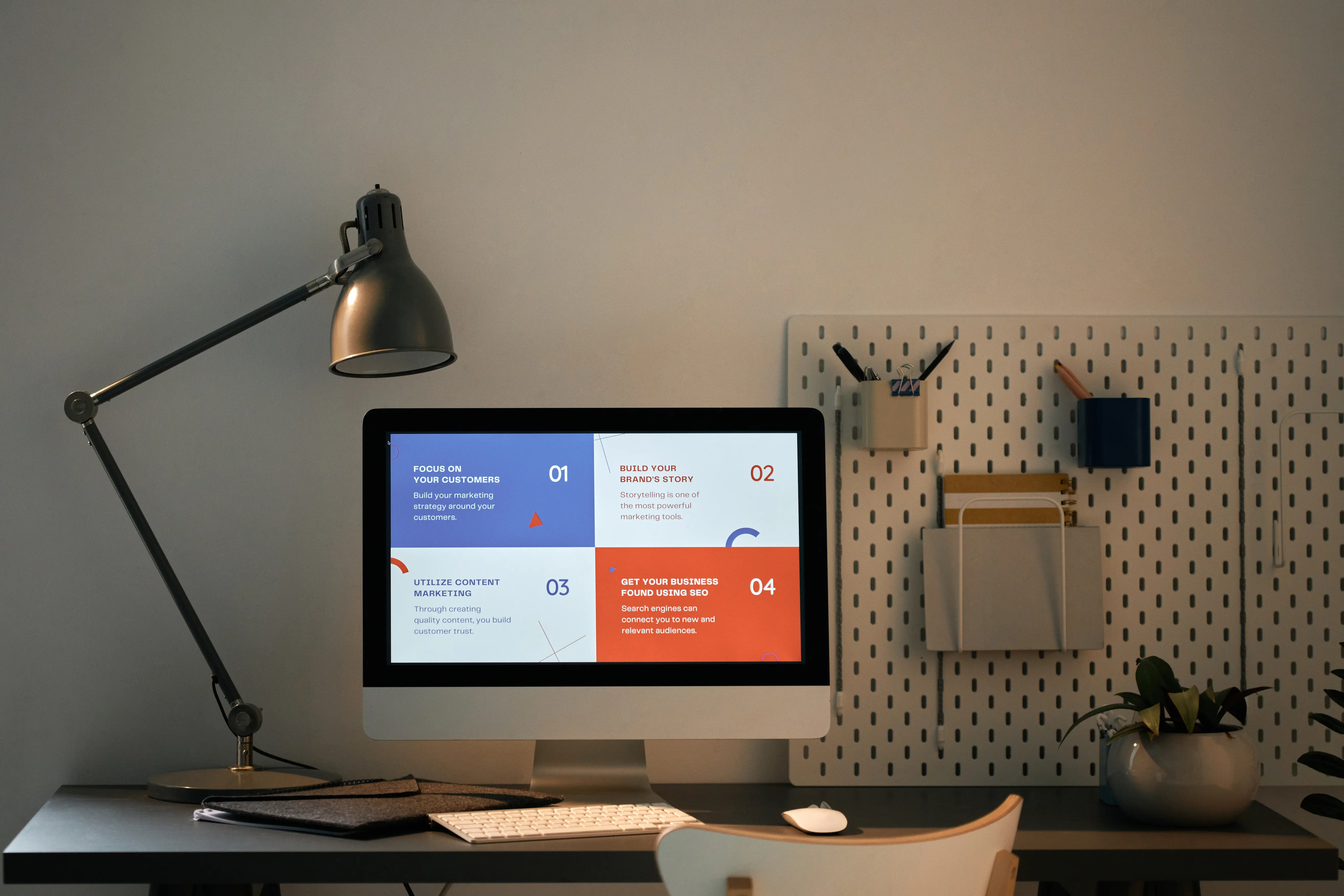 A minimalist workspace featuring a desktop computer displaying marketing strategy principles, SEO planning, content marketing, and brand development concepts.