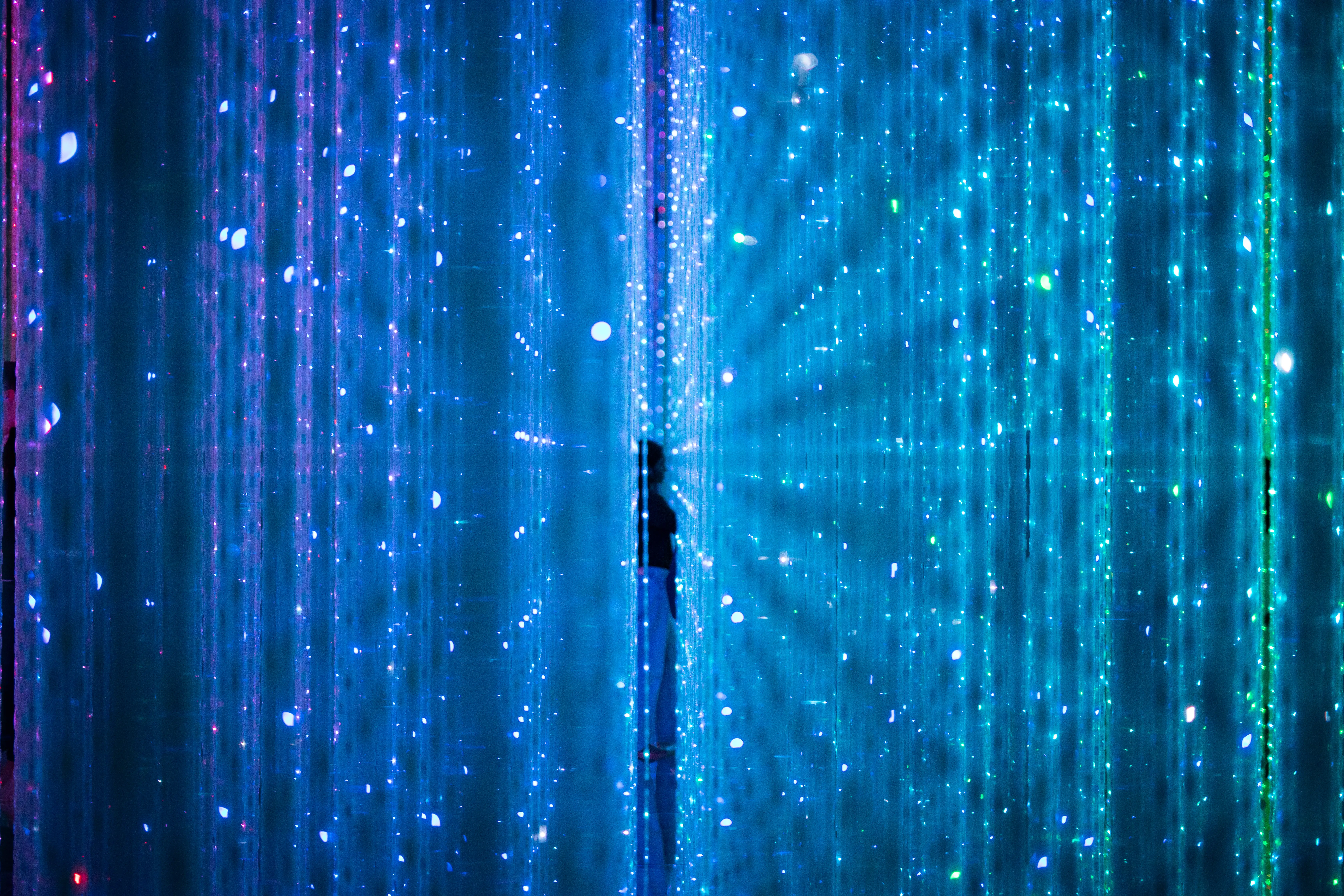 A silhouette standing inside a glowing blue immersive environment filled with digital light patterns and data streams, representing exploration, innovation, and the future of digital intelligence.